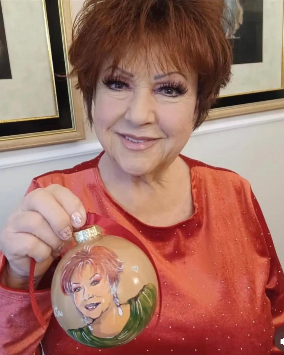 Orietta Berti tiene in mano la pallina di Natale dipinta a mano con il suo ritratto